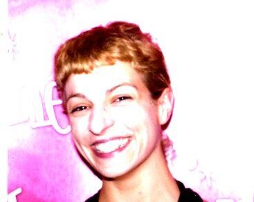 Roser Amills, sonriente y con el pelo corto, ante un fondo rosa
