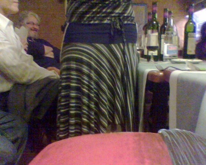 Cena de la fiesta del santo de Roser Amills en un restaurante, con una mujer de falda de rayas de pie junto a la mesa, en octubre de 2007