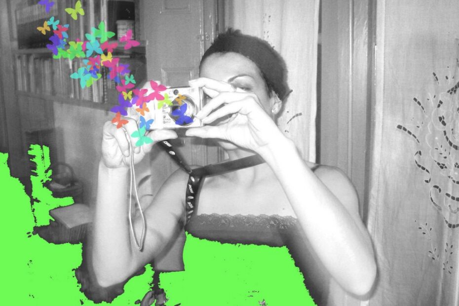Roser Amills fotografiando con una cámara compacta, en una foto en blanco y negro retocada con verde y mariposas de colores