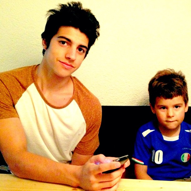 Marcel y Juan, los hijos de Roser Amills, sentados a una mesa de madera, julio de 2012