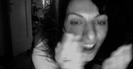 Retrato en blanco y negro de Roser Amills riendo y tapándose con la mano