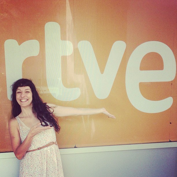 Roser Amills sonriente señala el logotipo de RTVE en los estudios de RNE-Ràdio 4, en agosto de 2013