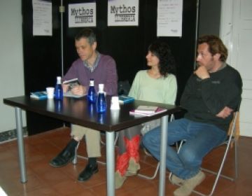 Roser Amills a la taula de la llibreria Mythos de Sant Cugat, amb Santi Borrell i Lluís Calvo, davant dels cartells de la llibreria
