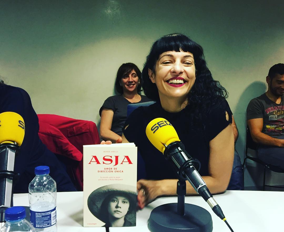 Roser Amills sonríe ante un micrófono de la SER, con un ejemplar de Asja sobre la mesa