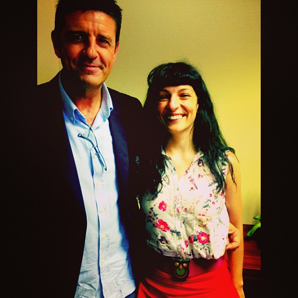 Roser Amills, con blusa de flores y falda roja, sonríe junto a un hombre con americana azul y camisa celeste