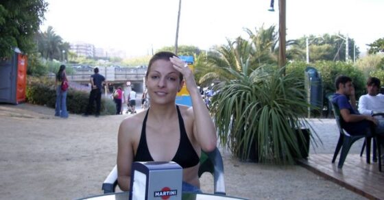 Roser Amills en bañador negro, sentada en una terraza de playa con un servilletero de Martini, en el verano de 2007
