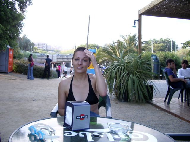 Roser Amills en bañador negro, sentada en una terraza de playa con un servilletero de Martini, en el verano de 2007