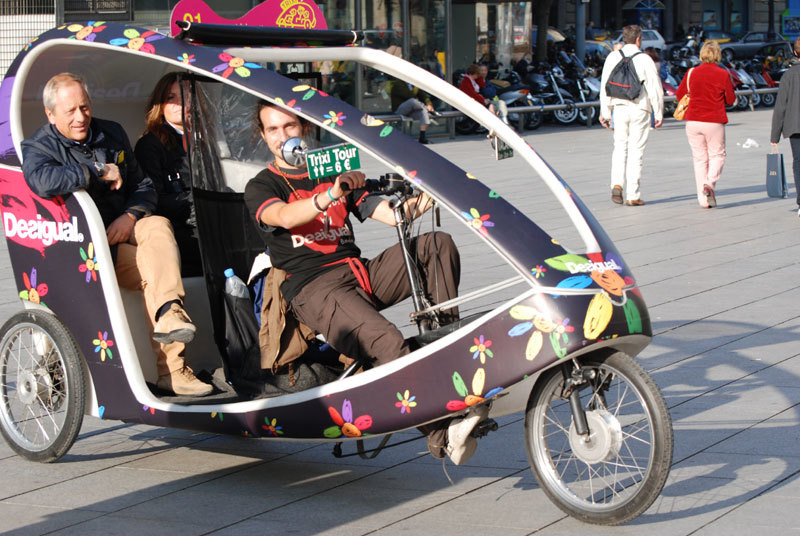 Un trixi, bicitaxi turístic, amb passatgers pels carrers de Barcelona
