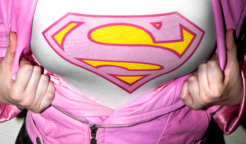 Una noia obre una jaqueta rosa i mostra una samarreta amb l’escut de Superman